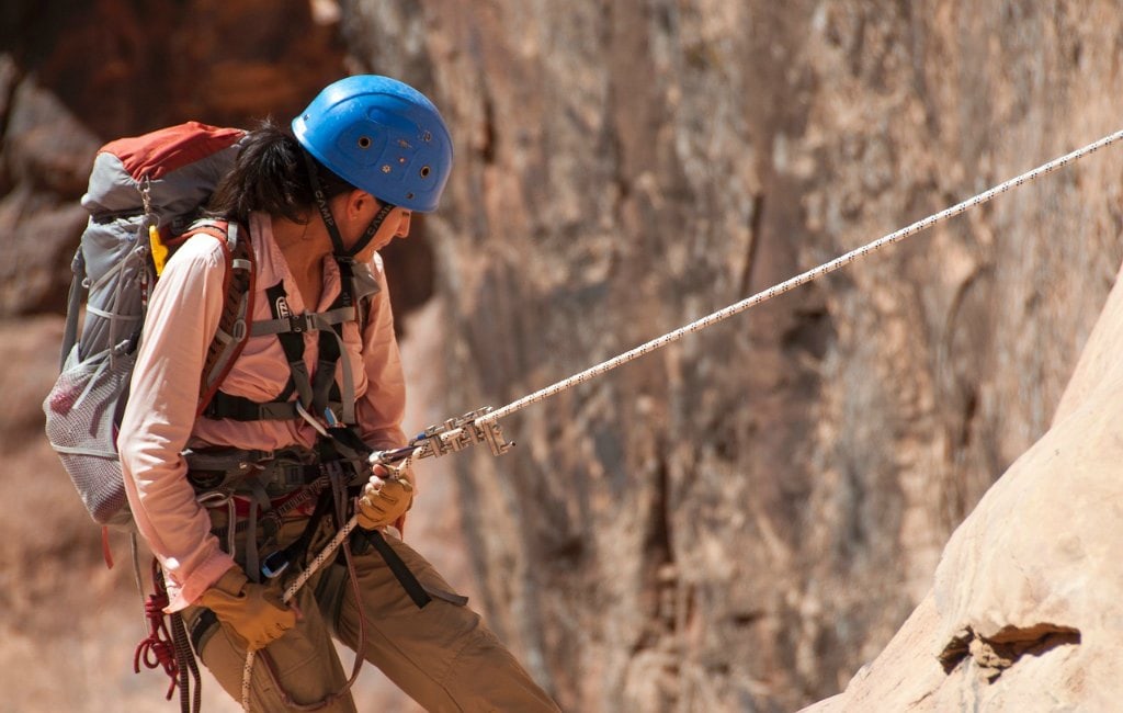 girl climbing mountain rope blue helmet