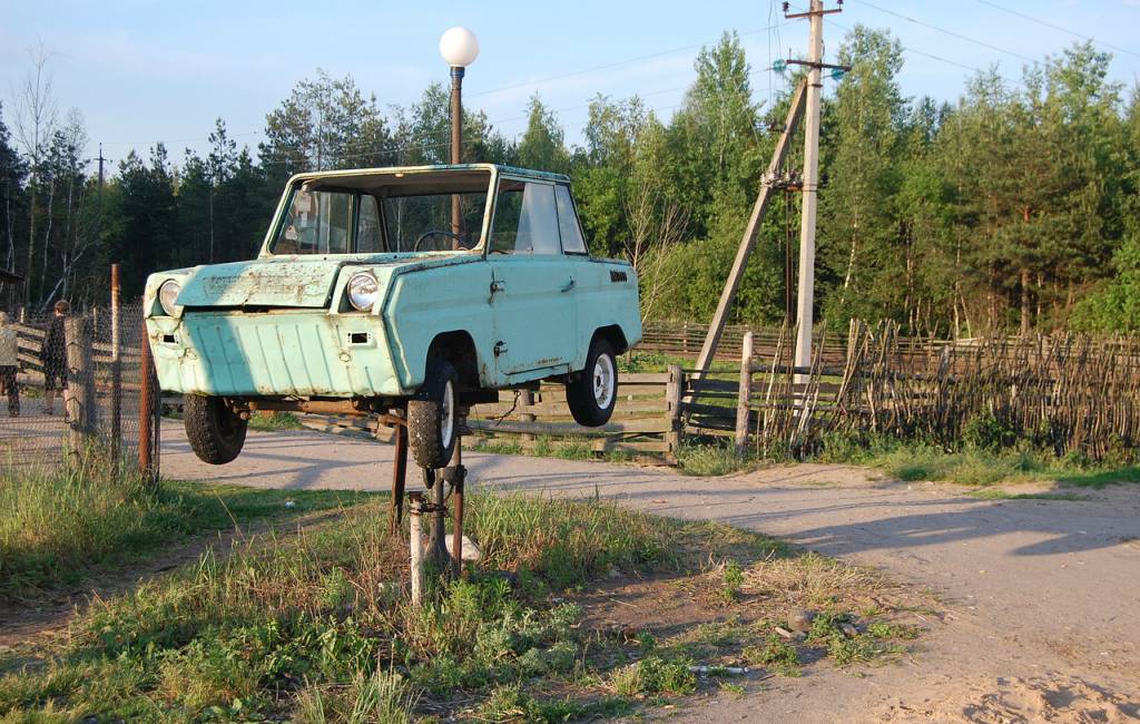 car hanging on tube light pole on road side