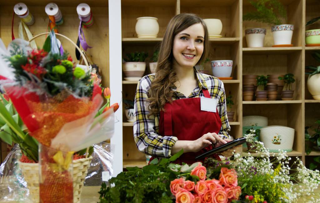 sales girl selling gift items in gift shop standing in front of flower